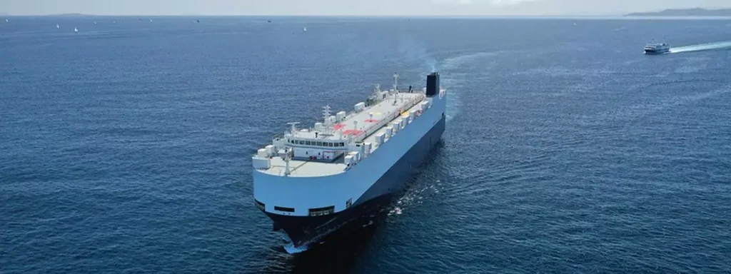 RoRo ship on the ocean followed by smaller boat.